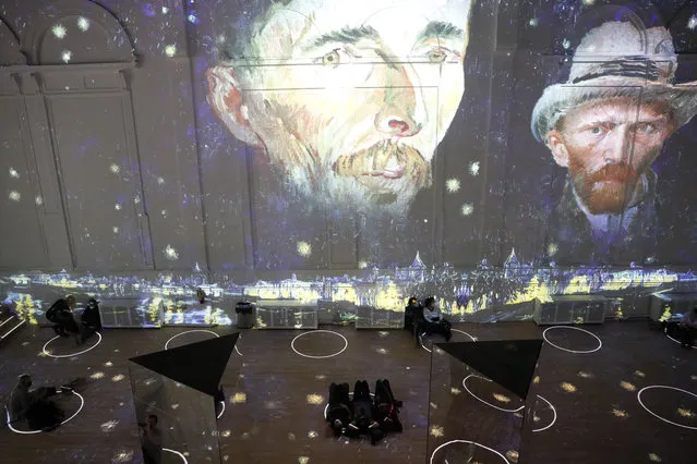 Patrons socially distance as they look at the moving images cast on the walls, floors and reflecting mirrors during a virtual display titled “Immersive Van Gogh” on Thursday, February 18, 2021, at the Lighthouse ArtSpace, in Chicago. (Photo by Shafkat Anowar/AP Photo)