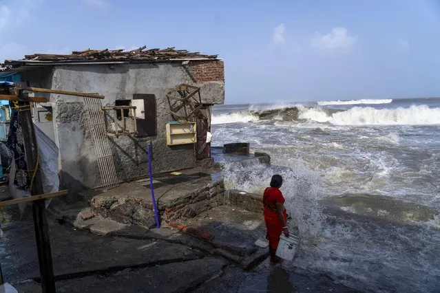 A woman stands next to her house as high tide waves hit the Arabian Sea coast in Mumbai, India, Tuesday, June 13, 2023. India and Pakistan braced for the first severe cyclone this year expected to hit their coastal regions later this week, as authorities on Monday halted fishing activities, deployed rescue personnel and announced evacuation plans for those at risk. From the Arabian Sea, Cyclone Biparjoy is aiming at Pakistan's southern Sindh province and the coastline of the western Indian state of Gujarat. (Photo by Rafiq Maqbool/AP Photo)