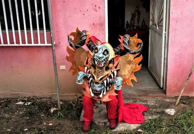 A member of the Dancing Devils of Yare prepares to participate in a mass to receive the blessing of the “Santisimo Sacramento del Altar” in San Francisco de Yare, Venezuela, as part of the Corpus Christi celebration on June 8, 2023. Devotees disguised as devils, dressed almost completely in red and wearing colourful masks, dance giving their devotion to Jesus, to the Holy Sacrament and to their patron saint San Francisco de Paula, paying promises for health miracles. (Photo by Yuri Cortez/AFP Photo)