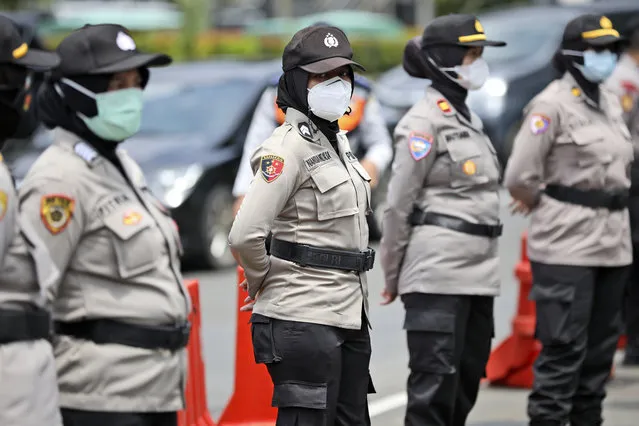 Police officers wearing masks to curb the spread of coronavirus outbreak stand guard during a rally celebrating the International Women's Day in Jakarta, Indonesia, Monday, March 8, 2021. (Photo by Dita Alangkara/AP Photo)