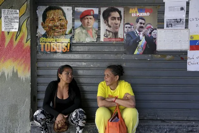 Women talk while seated under images of Venezuela's late President Hugo Chavez, national hero Simon Bolivar (2nd R) and Venezuela's current President Nicolas Maduro (R), close to the National Assembly building that was in session in Caracas December 22, 2015. (Photo by Marco Bello/Reuters)