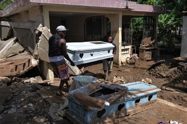 Two men carry a coffin next to a damaged house on a muddy street from heavy rains, in Leogane, Haiti, 06 June 2023. The heavy downpours registered in Haiti during the last few days have left at least 51 dead, 18 missing and 140 injured, the Civil Protection Directorate (DPC) reported on 06 June in a report that does not reflect the effects of an earthquake registered this morning in the southwest of the country. (Photo by Johnson Sabin/EPA/EFE)
