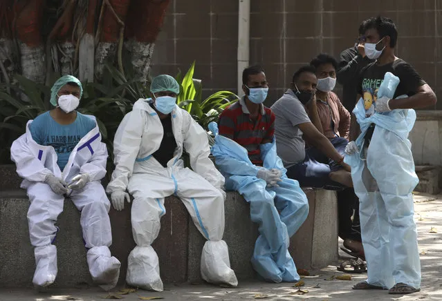 Health workers take rest in between cremating COVID 19 victims in New Delhi, India, Monday, April 19, 2021. New Delhi has imposed a weeklong lockdown to prevent the collapse of the Indian capital's health system amid an explosive surge in coronavirus cases. Authorities said Monday that hospitals have been pushed to their limit. India now has reported more than 15 million coronavirus infections, a total second only to the United States. (Photo by Manish Swarup/AP Photo)