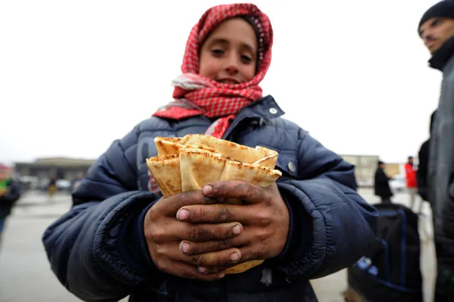 A Syrian boy evacuated from eastern Aleppo, poses carrying bread in government controlled Jibreen area in Aleppo, Syria November 30, 2016. (Photo by Omar Sanadiki/Reuters)