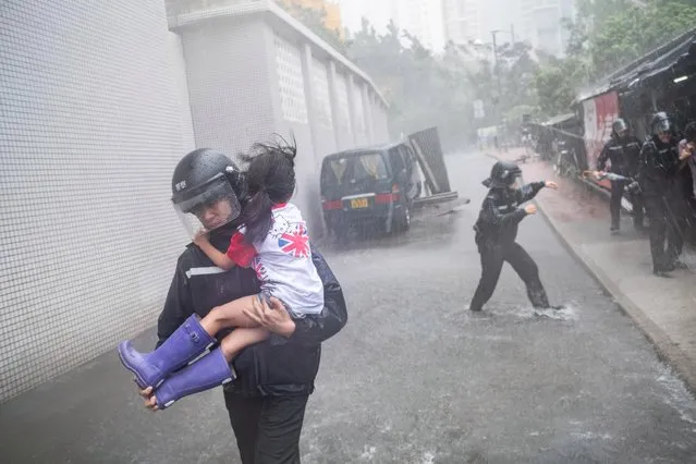 Police officers carry a girl out of a collapsed school on September 16, 2018 in Hong Kong, Hong Kong. City officials raised the storm alert to T10, it's highest level, as Typhoon Mangkhut landed on Hong Kong. The strongest tropical storm of the season so far, with winds as fast as 200 kilometres per hour, Mangkhut has reportedly killed at least 25 people in the Philippines as it continues it's path towards southern China. (Photo by Lam Yik Fei/Getty Images)