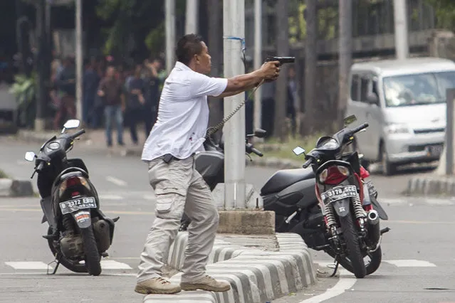 A plainclothes police officer aims his gun at attackers during a gun battle following explosions in Jakarta, Indonesia Thursday, January 14, 2016. Attackers set off explosions at a Starbucks cafe in a bustling shopping area in Indonesia's capital and waged gunbattles with police Thursday, leaving bodies in the streets as office workers watched in terror from high-rise buildings. (Photo by AP Photo)