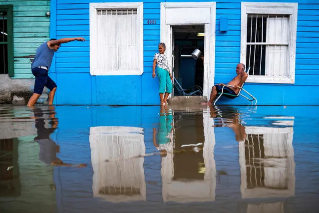A couple remains outside their house in a flooded area of Batabano, Mayabeque Province, Cuba, on August 28, 2023, as Tropical Storm Idalia approaches the western tip of the island nation. (Photo by Yamil Lage/AFP Photo)