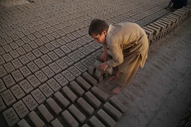 An Afghan boy works at a brick kiln in Sarhood district of Nangarhar province, Afghanistan, 10 June 2021. Labourers, most of whom work barefoot and without gloves, earn from three to seven US dollars a day depending on their working hours and the number of bricks they make, some of them children as young as four or five years old. (Photo by Ghulamullah Habibi/EPA/EFE)