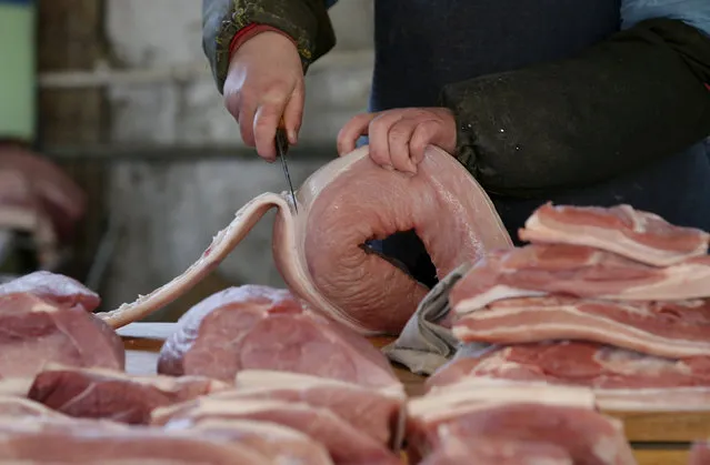 A butcher cuts a piece of pork at a market in Beijing, China March 25, 2016. (Photo by Jason Lee/Reuters)