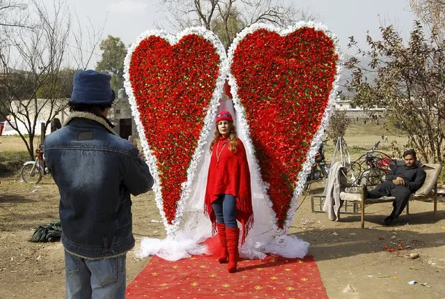 An Afghan man takes a picture of his sister in front of large heart shaped flower arrangement at a flower market on Valentine's Day in Islamabad, Pakistan February 14, 2016. (Photo by Akhtar Soomro/Reuters)