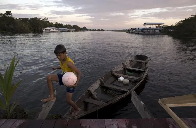 A boy arrives to a driftwood soccer court, on the banks of the Rio Negro or Black River in Catalao community near Manaus, in Amazonas state April 4, 2015. Residents of Catalao, a village of houseboats, built a floating wooden soccer court, since the village field was flooded by the full Rio Negro. According to the Geological Survey of Brazil (CPRM), the full Rio Negro this year is expected to reach close to the record occurred in 2012, when the river reached the quota of 29.97 meters. (Photo by Bruno Kelly/Reuters)