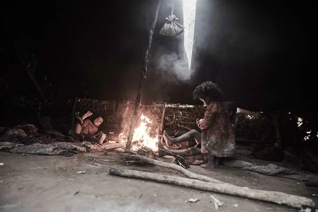 Children gather around a small fire underneath one of the Raute's tents in Accham District, Nepal, January 2016. (Photo by Jan Moller Hansen/Barcroft Images)