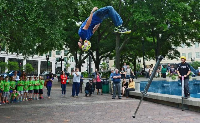 XPogo athlete Ryan O'Malley flips off his pogo stick as he completes a routine during his extreme pogo demonstration in Hemming Park, in Jacksonville, Fla., Thursday, April 16, 2015. (Photo by Bob Mack/The Florida Times-Union via AP Photo)
