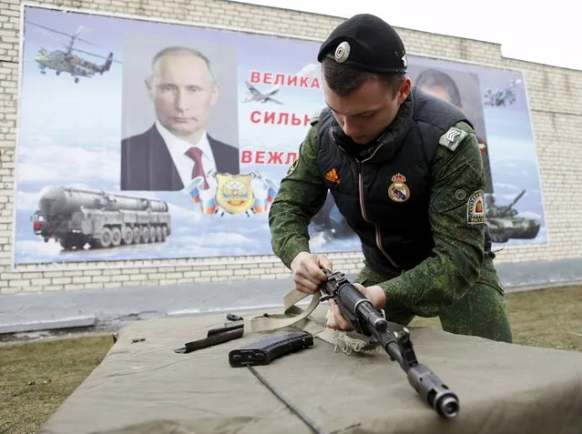 A member of a youth military club assembles a Kalashnikov automatic rifle during sport and military competitions among pre-enlistment aged youth, with a banner depicting Russian President Vladimir Putin seen in the background, in the southern city of Stavropol, Russia, February 25, 2016. (Photo by Eduard Korniyenko/Reuters)