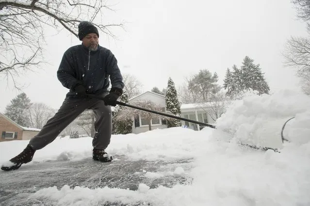 Rick Gibson shovels the snow from his neighbor's driveway on West Kalong Circle in Southfield, Michigan on Sunday, January 5, 2014, as metro Detroit digs out from a severe winter snow storm. (Photo by David Guralnick/AP Photo/The Detroit News)