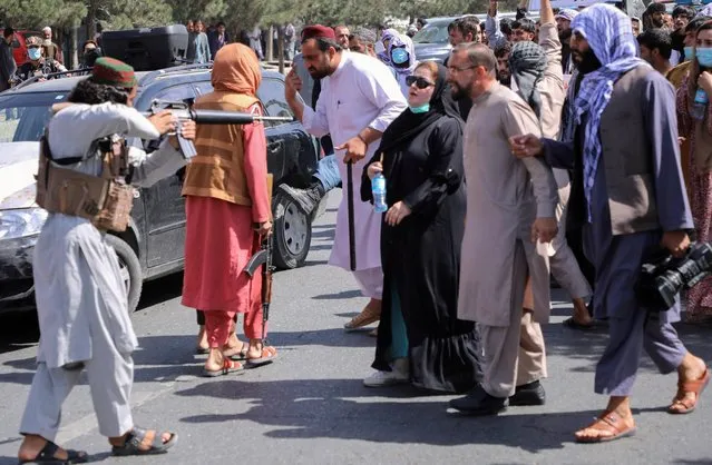 A member of the Taliban forces points his gun at protesters, as Afghan demonstrators shout slogans during an anti-Pakistan protest, near the Pakistan embassy in Kabul, Afghanistan on September 7, 2021. (Photo by Reuters/Stringer)