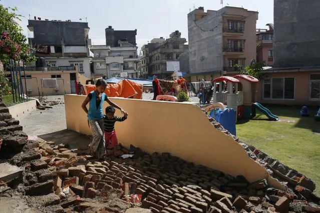 A young girl walks with a boy over a collapsed school playground in Kathmandu, Nepal, Monday, April 27, 2015. (Photo by Wally Santana/AP Photo)