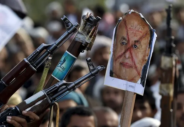 Followers of the Houthi group aim their weapons at a defaced poster of Yemen's President Abd-Rabbu Mansour Hadi during a demonstration against the air strikes by the Saudi-led coalition in Sanaa April 27, 2015. The words on the poster read, “Murderer of the children”. (Photo by Khaled Abdullah/Reuters)