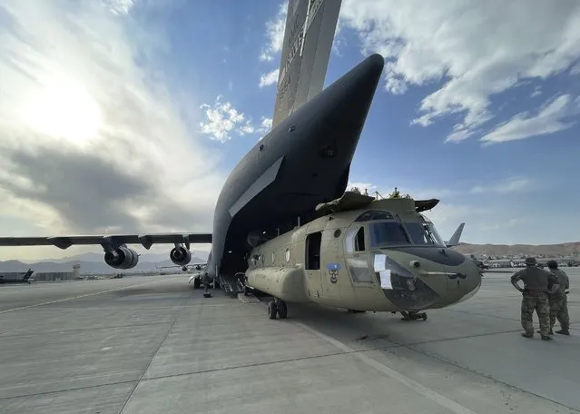 In this image provided by the Department of Defense, a CH-47 Chinook from the 82nd Combat Aviation Brigade, 82nd Airborne Division is loaded onto a U.S. Air Force C-17 Globemaster III at Hamid Karzai International Airport in Kabul, Afghanistan, Saturday, August 28, 2021. (Photo by Department of Defense via AP Photo)