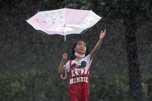 A girl braves the rain at a park near the waterfront of Victoria Harbour in Hong Kong, Saturday, October 9, 2021. The Hong Kong Observatory issued the number 8 storm signal, as the tropical storm Lionrock was southwest of the regional financial hub, which has a population of 7.5 million. (Photo by Kin Cheung/AP Photo)