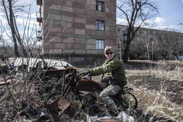 A Ukrainian solder sits atop of burned motorcycle in the village of Zolote 4, eastern Ukraine, Friday, March 29, 2019. Five years after a deadly separatist conflict in eastern Ukraine, the front line between government forces and Russia-backed separatists has become a de-facto border, cutting off a generation of first-time voters from Sunday's presidential election. (Photo by Evgeniy Maloletka/AP Photo)