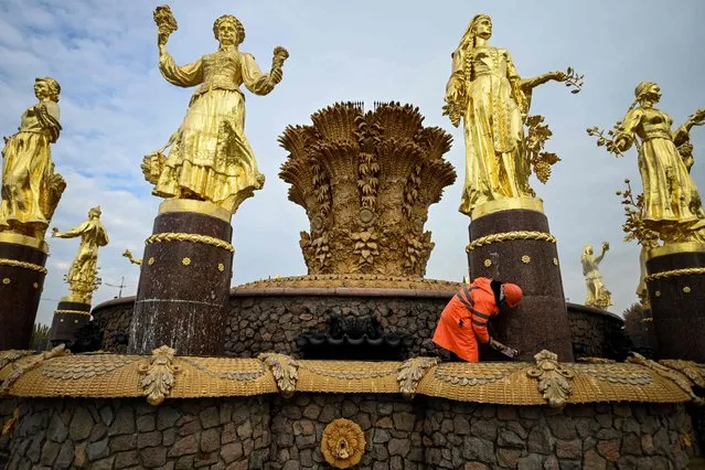 A municipal worker cleans the Druzhba Narodov (Friendship of Nations) fountain at the All-Russia Exhibition Centre (VDNKh) as part of the city's preparations for winter in Moscow on October 13, 2021. The fountain was installed at the All-Russia Exhibition Centre (VDNKh), a trade show and amusement park, in 1954, with 16 gilded bronze sculptures of young women representing 16 republics of the USSR around the oval fountain bowl featuring a wheat sheaf. (Photo by Kirill Kudryavtsev/AFP Photo)
