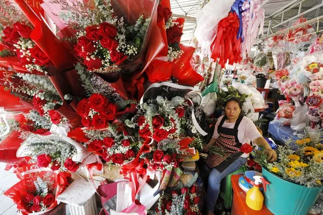 A vendor prepares roses for sale ahead of Valentine's Day at a flower market in Bangkok, Thailand, 13 February 2024. People all over the world prepare to celebrate Valentine's Day annually on 14 February, by giving flowers, chocolates, or cards to loved ones. (Photo by Narong Sangnak/EPA)