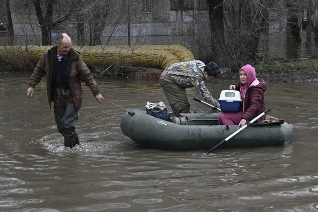 A man pulls a rubber boat carrying a woman with a cat through a flooded street after part of a dam burst, in Orsk, Russia on April 7, 2024. State media say Russia's government has declared the situation in flood-hit areas in the Orenburg region a federal emergency. The floods, caused by rising water levels in the Ural River, forced over 4,000 people, including over 800 children, to evacuate, the regional government said. (Photo by Anatoly Zhdanov/Kommersant Publishing House via AP Photo)