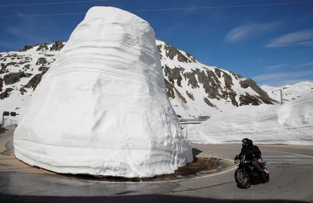 Walls of snow are seen beside as people ride on a bike during sunny weather on the St. Gotthard mountainpass road, Switzerland on June 1, 2019. (Photo by Arnd Wiegmann/Reuters)