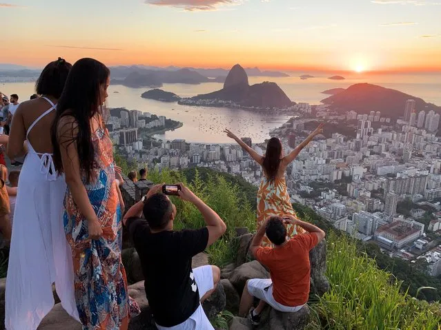 People enjoy the sunrise from Dona Marta lookout, with Sugarloaf mountain in the background in Rio de Janeiro, Brazil on December 31, 2020. (Photo by Sergio Queiroz/Reuters)