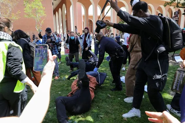 People take pictures as USC Safety officers try to disperse students who protest in support of Palestinians, at the University of Southern California's Alumni Park, amid the ongoing conflict between Israel and the Palestinian Islamist group Hamas, in Los Angeles, California, April 24, 2024. (Photo by Zaydee Sanchez/Reuters)