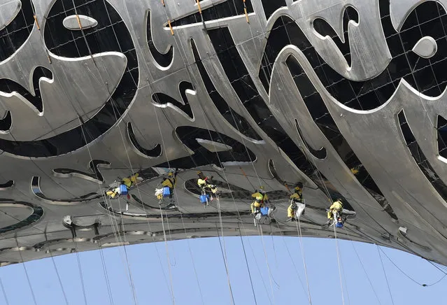 Laborers hang from The Museum of the Future, a museum of innovation and design currently under construction in Dubai, United Arab Emirates, Tuesday, February 2, 2021. (Photo by Kamran Jebreili/AP Photo)