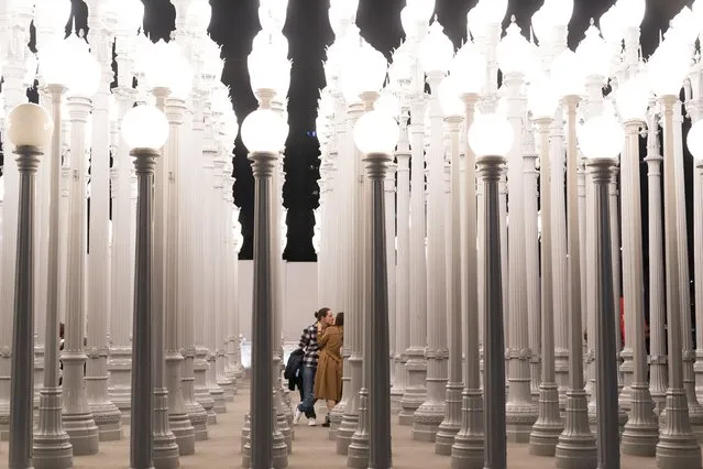 A couple kisses while visiting Chris Burden's installation “Urban Light” at the Los Angeles County Museum of Art in Los Angeles, Friday, January 14, 2022. (Photo by Jae C. Hong/AP Photo)