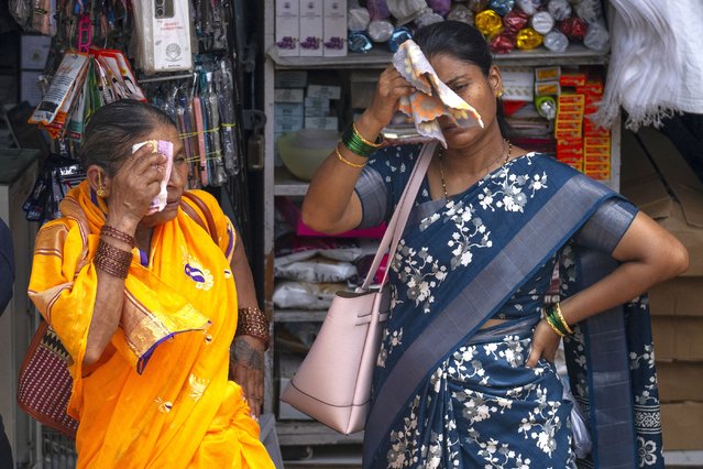 Women wipe the sweat from their faces as they wait for bus on a hot and humid summer day in Mumbai, India, Thursday, May 23, 2024. (Photo by Rafiq Maqbool/AP Photo)