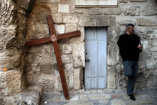 A man stands next to a Christian cross outside the Church of the Holy Sepulchre in Jerusalem's old city on March 26, 2017. (Photo by Thomas Coex/AFP Photo)
