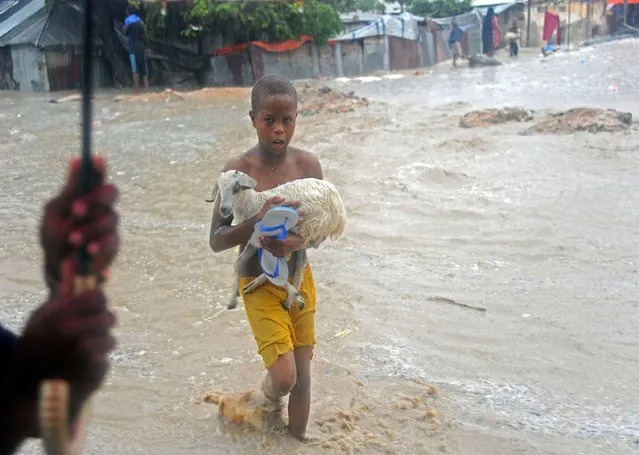 A young  boy carries a goat across a flooded street of Mogadishu, Somalia on May 3, 2016 following heavy rainfall overnight. (Photo by Mohamed Abdiwahab/AFP Photo)