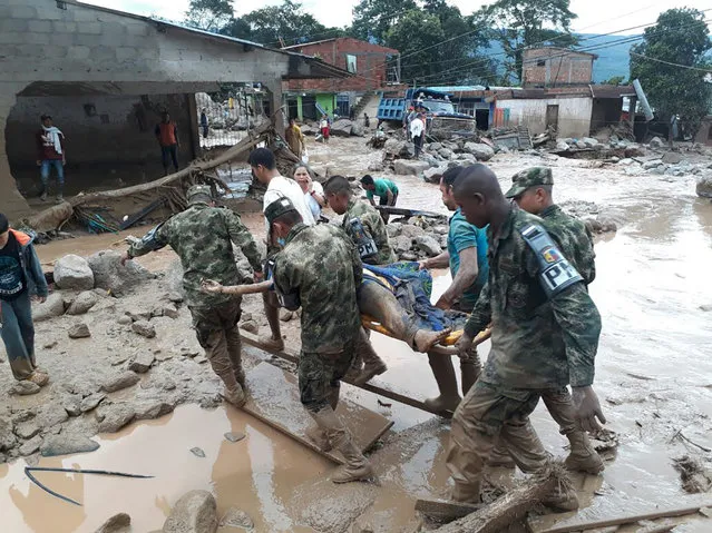 In this handout photo released by the Colombian National Army, soldiers carry a victim on a stretcher, in Mocoa, Colombia, Saturday, April 1, 2017, after an avalanche of water from an overflowing river swept through the city as people slept. (Photo by Colombian Army Photo via AP Photo)