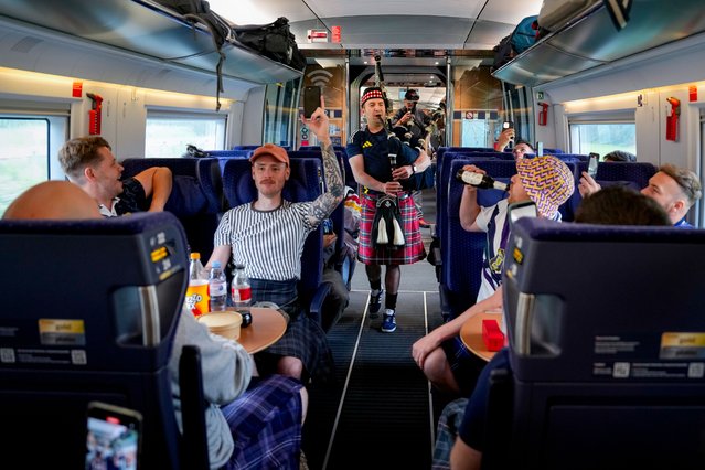 A man plays the bagpipes as passengers cheer and take pictures in a train heading from Berlin to Munich, in Germany, Friday, June 14, 2024 before a Group A match between Germany and Scotland at the Euro 2024 soccer tournament. (Photo by Markus Schreiber/AP Photo)
