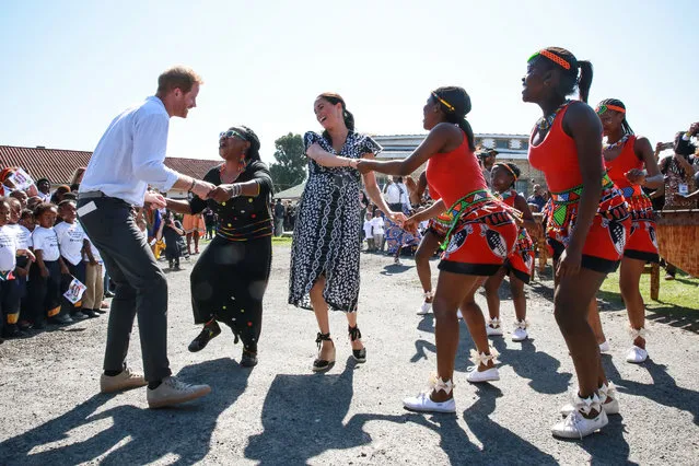Prince Harry, Duke of Sussex and Meghan, Duchess of Sussex dance as they arrive for a visit to the “Justice desk”, an NGO in the township of Nyanga in Cape Town, as they begin their tour of the region on September 23, 2019. Britain's Prince Harry and his wife Meghan arrived in South Africa on September 23, launching their first official family visit in the coastal city of Cape Town. The 10-day trip began with an education workshop in Nyanga, a township crippled by gang violence and crime that sits on the outskirts of the city. (Photo by Betram Malgas/AFP Photo/Pool)