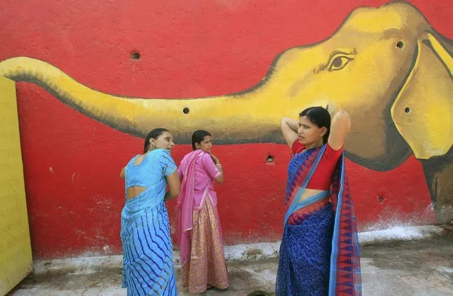 Hindu women comb their hair in front of a mural after taking a holy dip in the Shipra river during Simhastha Kumbh Mela in Ujjain, India, May 4, 2016. (Photo by Jitendra Prakash/Reuters)