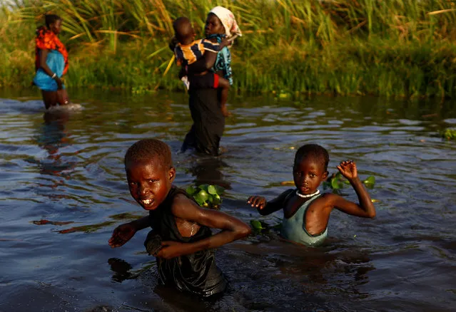 Children cross a body of water to reach a registration area prior to a food distribution carried out by the United Nations World Food Programme (WFP) in Thonyor, Leer county, South Sudan, February 25, 2017. (Photo by Siegfried Modola/Reuters)