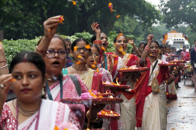 Hindu devotees toss flower petals as they lead the annual Ratha Yatra or chariot festival in Kolkata, India, July 7, 2024. (Photo by Bikas Das/AP Photo)