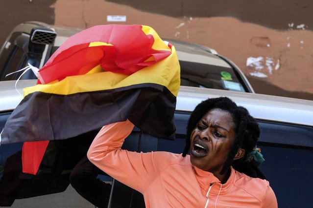 A protester holding a her country national flag during the anticorruption protest in Kampala, Uganda, Tuesday, July 23, 2024. Ugandan security forces on Tuesday arrested dozens of people who tried to walk to the parliament building to demonstrate against high-level corruption in protests that authorities say are unlawful. (Photo by Hajarah Nalwadda/AP Photo)