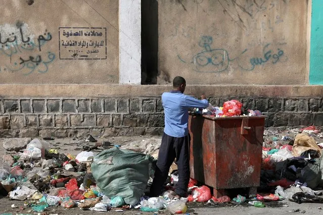 Ismail Hassan, displaced by war in the Red Sea port city of Hodeidah, collects recyclables from a garbage container in Sanaa, Yemen on January 17, 2022. (Photo by Khaled Abdullah/Reuters)