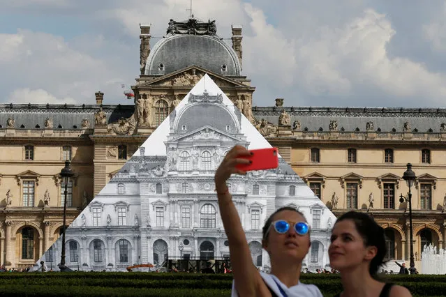 Tourists take a selfie with French artist JR's latest work, an image of the facade of Paris' Louvre that covers the museum's Pyramid entrance in Paris, France, May 25, 2016. (Photo by Pascal Rossignol/Reuters)