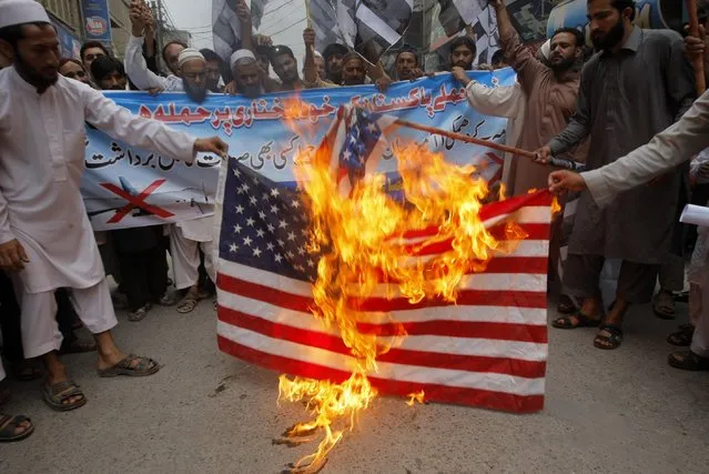 Supporters of Pakistani religious group Jamaat-ud-Dawa burn representation of an American flag during a protest rally to condemn the U.S. drone strike in Pakistani territory which killed Taliban leader Mullah Mansour, Friday, May 27, 2016 in Peshawar, Pakistan. A nation-wide protests were observed in Pakistan condemn the drone attack on Pakistani soil. (Photo by Mohammad Sajjad/AP Photo)