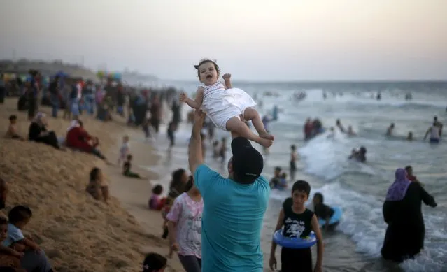 A Palestinian man lifts his daughter as he enjoys the warm weather with his family on a beach along the Mediterranean Sea in the northern Gaza Strip July 24, 2015. (Photo by Mohammed Salem/Reuters)