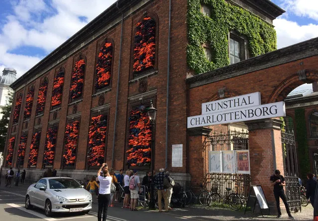People view the new artwork by Chinese dissident artist Ai Weiwei, entitled “Soleil Levant” (Sunrise in French) made from over 3,500 lifejackets discarded by migrants on the Greek island of Lesbos, following its official inauguration at Copenhagen’s Kunsthal Charlottenborg museum in Copenhagen, Denmark, Tuesday June 20, 2017. Weiwei has barricaded the windows of the museum for his provocative new artwork as a striking reminder of the ongoing migrant crisis, inaugurated Tuesday on World Refugee Day. (Photo by James Brooks/AP Photo)