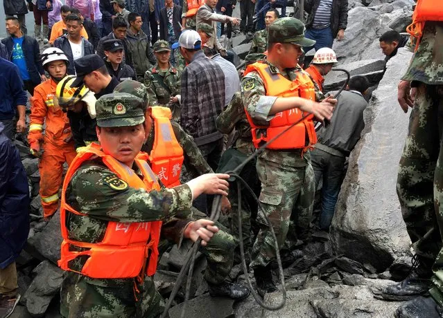 Chinese military police and rescue workers are seen at the site of a landslide in in Xinmo village, Diexi town of Maoxian county, Sichuan province on June 24, 2017. Around 100 people are feared buried after a landslide smashed through their village in southwest China's Sichuan Province early Saturday, local officials said, as they launched an emergency rescue operation. (Photo by AFP Photo/Stringer)