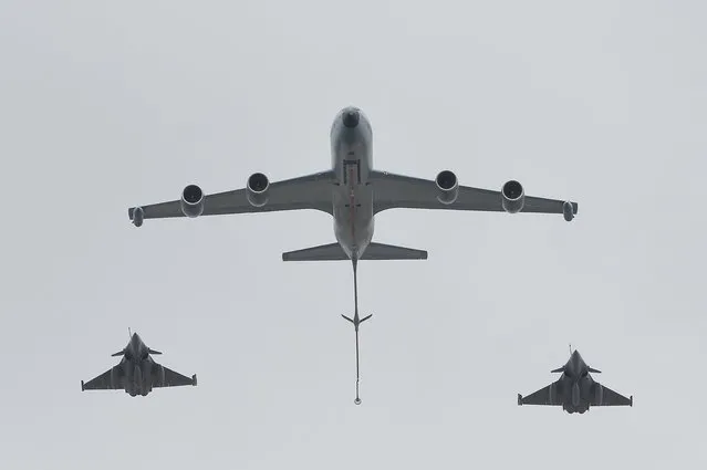 A Boeing C135 (C) refueling tanker followed by two Rafale fighter jets fly in formation over the Champs-Elysees avenue in Paris during the annual Bastille Day military parade, on July 14, 2014. (Photo by Miguel Medina/AFP Photo)